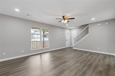 Unfurnished living room with ceiling fan, dark wood-style floors, baseboards, stairway, and recessed lighting
