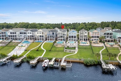 Aerial view of residential area with a large body of water, a pool area, and a tree filled landscape