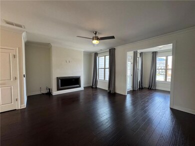 Unfurnished living room with ornamental molding, healthy amount of natural light, a fireplace, ceiling fan, and dark wood-style flooring