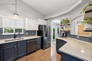 Kitchen with stainless steel appliances, white cabinetry, tasteful backsplash, open shelves, and vaulted ceiling