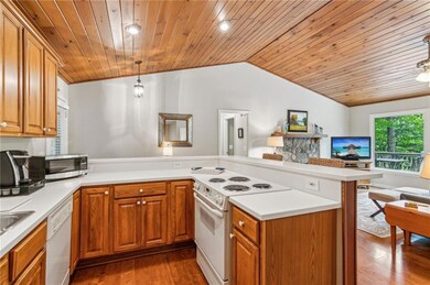Kitchen featuring white appliances, a peninsula, open floor plan, lofted ceiling, and wood ceiling