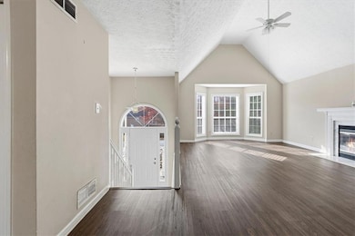 Entrance foyer featuring dark wood-style floors, a ceiling fan, a textured ceiling, high vaulted ceiling, and a high end fireplace