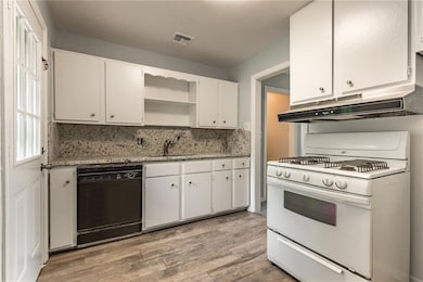 Kitchen featuring black dishwasher, white gas range oven, under cabinet range hood, open shelves, and white cabinetry