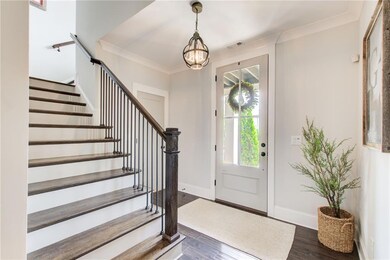 Entryway featuring a chandelier, stairway, dark wood-type flooring, baseboards, and crown molding