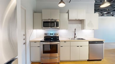 Kitchen featuring decorative backsplash, light cou