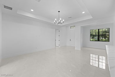 Spare room featuring a raised ceiling, a chandelie