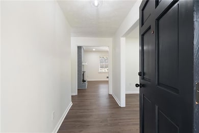 Hall with baseboards, a textured ceiling, and dark