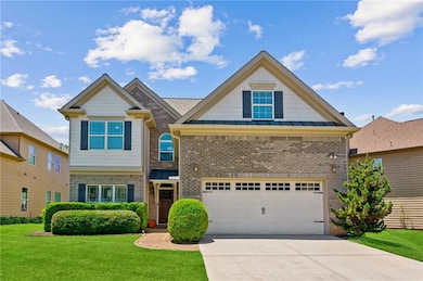 View of front of house with brick siding, a front yard, concrete driveway, a standing seam roof, and an attached garage