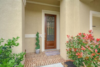 Brick decking and wood stained front door with glass and iron welcome you and your guests.