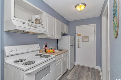 Kitchen with white cabinetry, white appliances, si