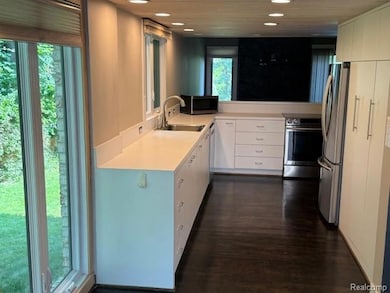 Kitchen featuring light countertops, appliances with stainless steel finishes, white cabinets, dark wood-style floors, and recessed lighting