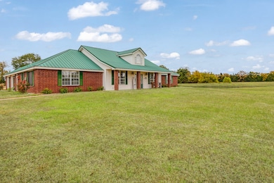 View of front facade featuring a front yard, a porch, a metal roof, and brick siding