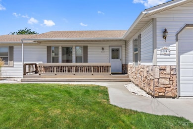 Entrance to property with a yard, a porch, stone siding, and a shingled roof