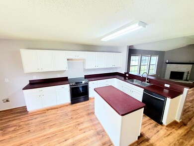 Kitchen with appliances with stainless steel finishes, light hardwood / wood-style floors, white cabinets, kitchen peninsula, and sink