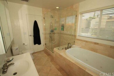 Beautiful travertine master bath has door to allow