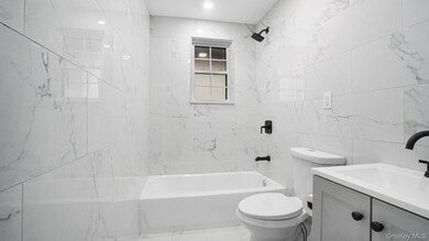 Bathroom with tile walls,  shower combination, and vanity
