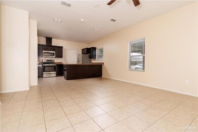 Kitchen featuring open floor plan, appliances with stainless steel finishes, dark brown cabinetry, light countertops, and light tile patterned floors