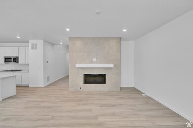 Unfurnished living room featuring light wood-type flooring, a fireplace, and recessed lighting