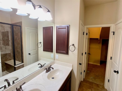 Bathroom featuring a shower stall, double vanity,