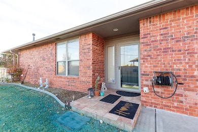View of exterior entry featuring brick siding, a patio area, and a yard