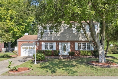 View of front facade featuring concrete driveway, an attached garage, and brick siding