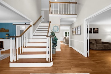 Bright two-story entryway with hardwood floors and updated lighting, with a private home office just off to the right behind double doors.