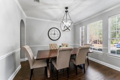 Beautiful formal dining room with statement lighting, refined crown molding, and large windows—ideal for gatherings and celebrations.