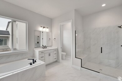 Bathroom featuring a bath, a marble finish shower, vanity, and light marble finish flooring