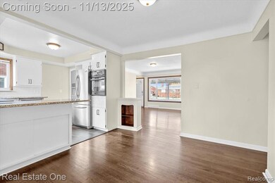 Kitchen featuring white cabinetry, backsplash, dark wood-type flooring, and stainless steel appliances