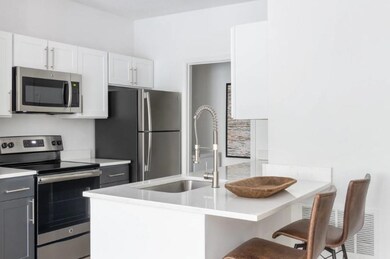 Kitchen featuring light countertops, a kitchen breakfast bar, stainless steel appliances, and a sink