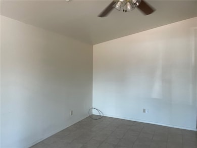 Empty room with a ceiling fan and tile patterned f
