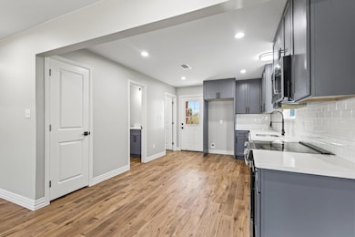 Kitchen with range with electric stovetop, light wood-style flooring, tasteful backsplash, recessed lighting, and light stone counters