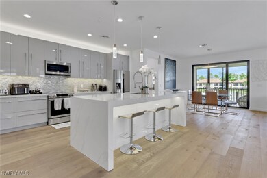 Kitchen featuring modern cabinets, hanging light fixtures, a kitchen bar, backsplash, and an island with sink