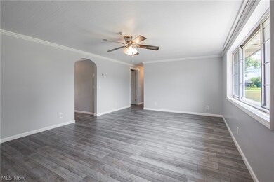 Empty room with ornamental molding, ceiling fan, and dark wood-type flooring