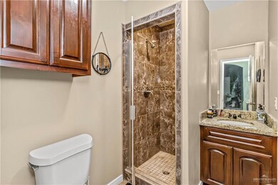 Bathroom with vanity with extensive cabinet space, walk in shower, and toilet