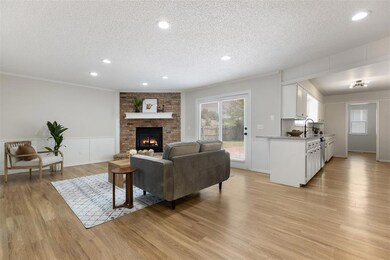 Living room with a textured ceiling, a fireplace, light wood-style flooring, recessed lighting, and a wainscoted wall