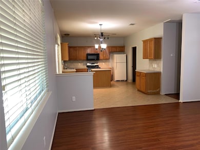Kitchen featuring freestanding refrigerator, brown cabinetry, a chandelier, and light countertops