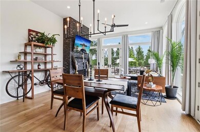 Dining space featuring light wood-style floors, a chandelier, recessed lighting, floor to ceiling windows, and a brick fireplace