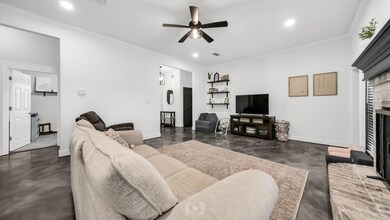Living room featuring ceiling fan, crown molding, and a stone fireplace