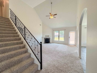 Unfurnished living room featuring carpet floors, a fireplace with flush hearth, high vaulted ceiling, stairway, and arched walkways