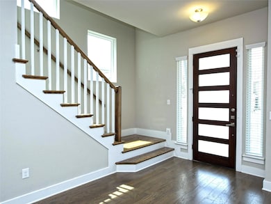 Foyer with plenty of natural light, dark wood finished floors, and stairway