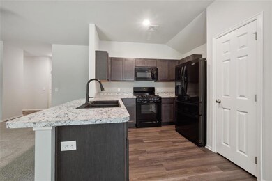 Kitchen with dark brown cabinets, sink, black appl