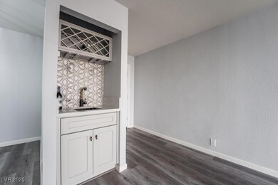 Indoor wet bar with dark wood-type flooring, baseb