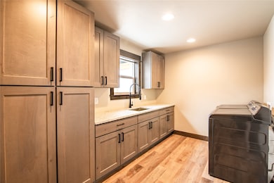 Laundry room with light wood-style flooring, cabinet space, washer and clothes dryer, and recessed lighting
