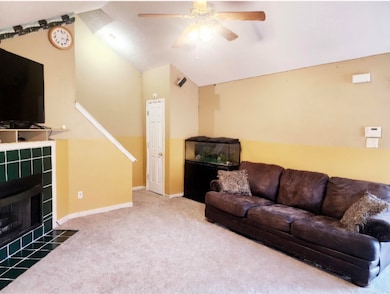 Carpeted living room with a fireplace, vaulted cei