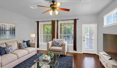 Living room with wood finished floors and a ceiling fan. Virtually staged.
