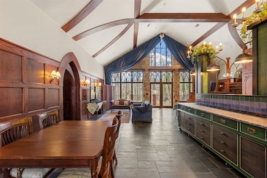 Kitchen, Living Room, Dining Room areaDining space featuring beam ceiling, high vaulted ceiling, dark tile flooring, and a chandelier