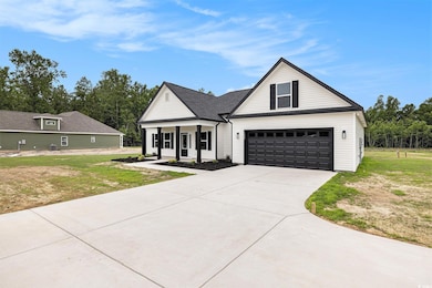 View of front of home featuring a front lawn, driveway, a garage, and covered porch