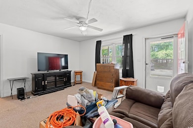Carpeted living room with a ceiling fan and a textured ceiling