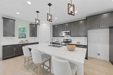 A welcoming kitchen with plenty of cabinet space, beautiful quartz counters, a roomy island for gathering, handy pantry, stainless steel appliances, pendant lights and recessed lighting